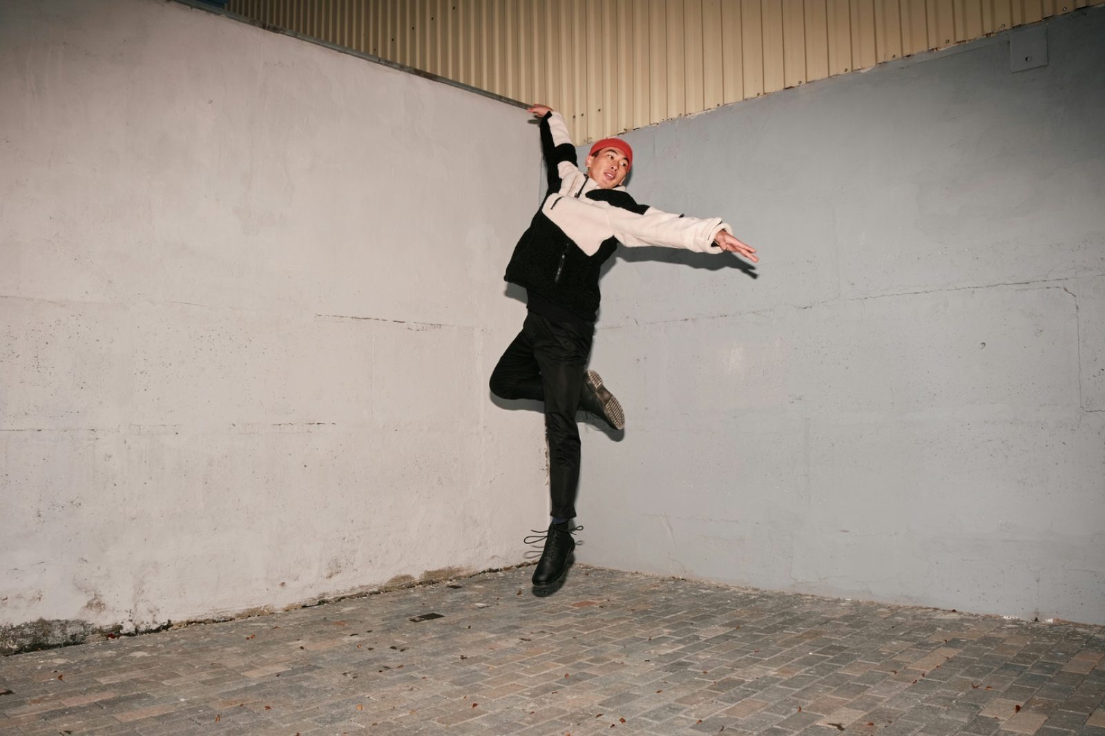 Analog flash photograph of a person jumping in front of a concrete wall