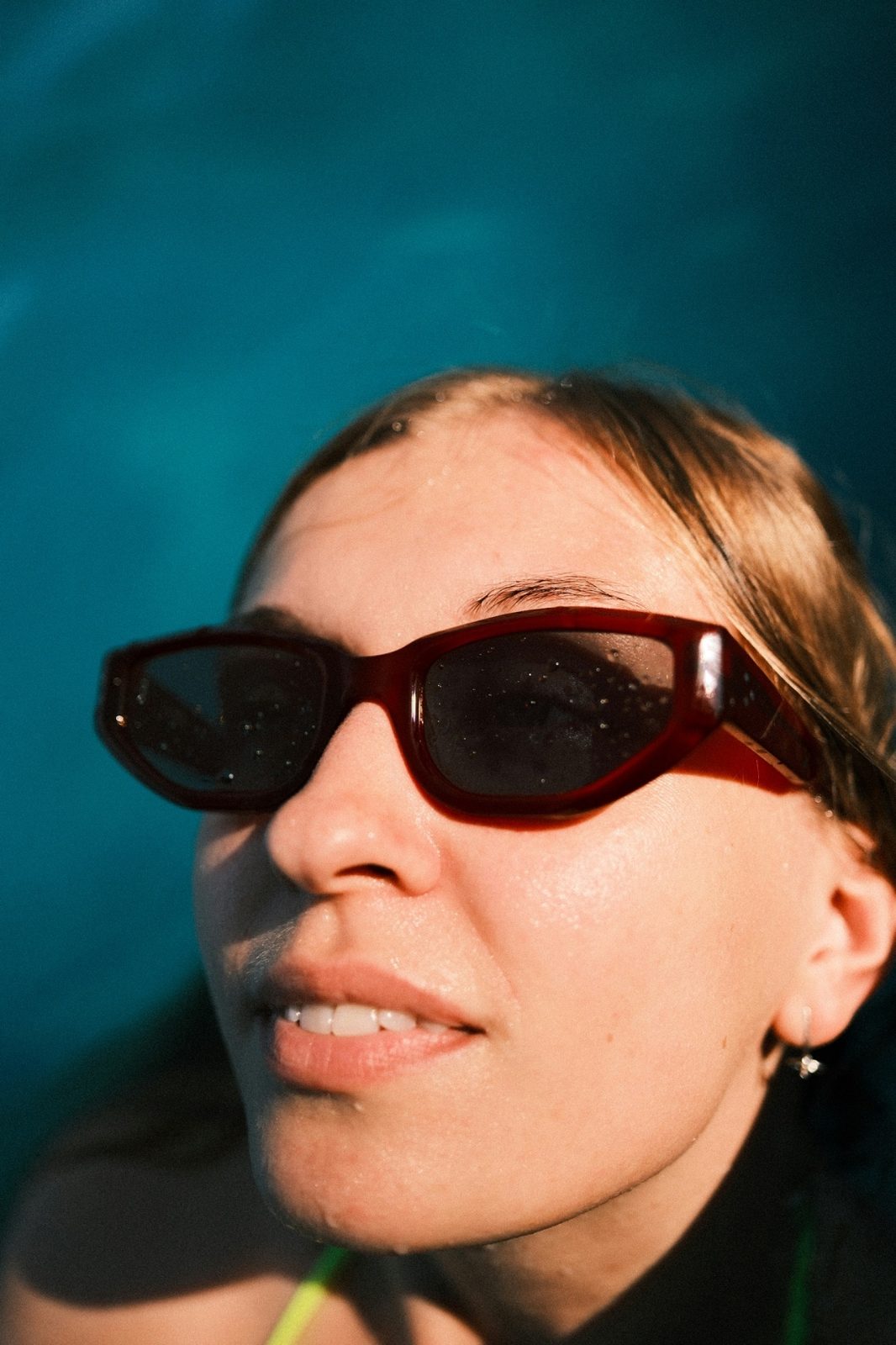 Analog portrait of a woman in dark sunglasses in front of deep blue water